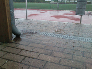 Das Bild zeigt das Ende einer Regenrinne aus dem das Wasser schießt. Der Gulli davor kann das Wasser nicht ganz fassen.