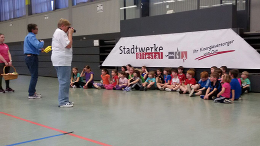 Die Kinder sitzen auf dem Hallenboden und warten auf die Siegerehrung.