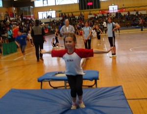 Kind, das gerade über ein Trampolin gesprungen ist und nun im Stand steht.